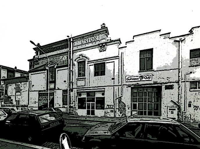 Illustration en noir et blanc dans le style BD représentant l'ancien bâtiment de la Chocolaterie de l'Union avant sa fermeture en 1960 avec deux voitures garées devant le long de la rue.